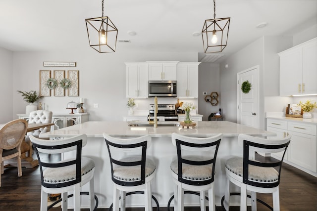 kitchen with dark hardwood / wood-style floors, decorative light fixtures, appliances with stainless steel finishes, and white cabinetry