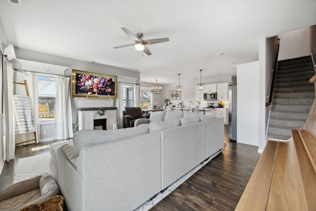 living room with dark hardwood / wood-style floors and ceiling fan with notable chandelier