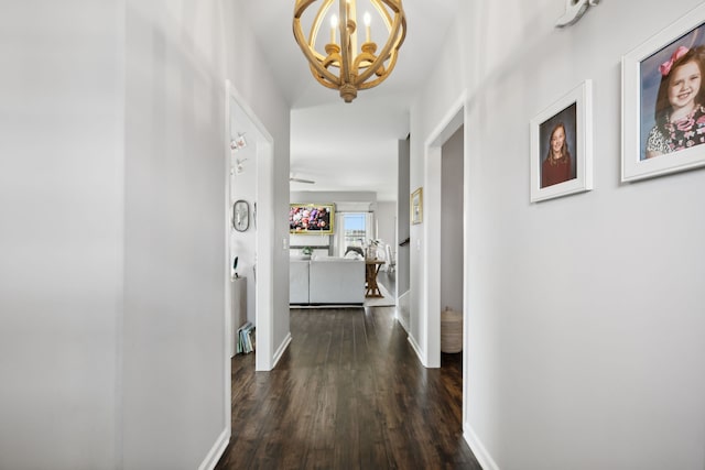 hallway with dark wood-type flooring and a chandelier