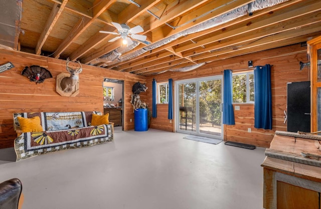 basement with a ceiling fan and wood walls