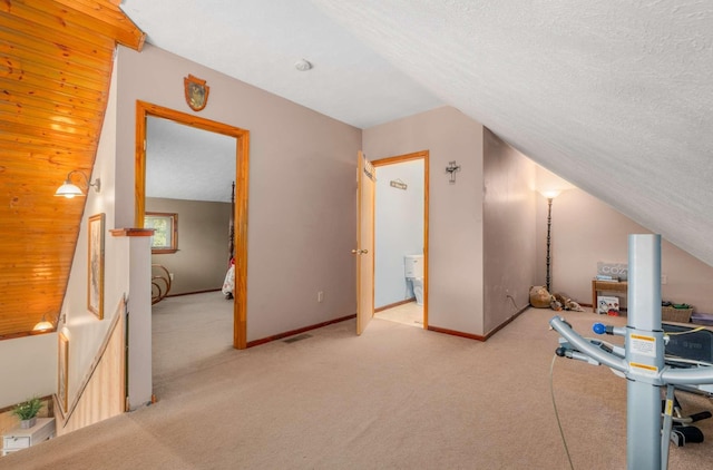 interior space featuring visible vents, light carpet, vaulted ceiling, a textured ceiling, and baseboards