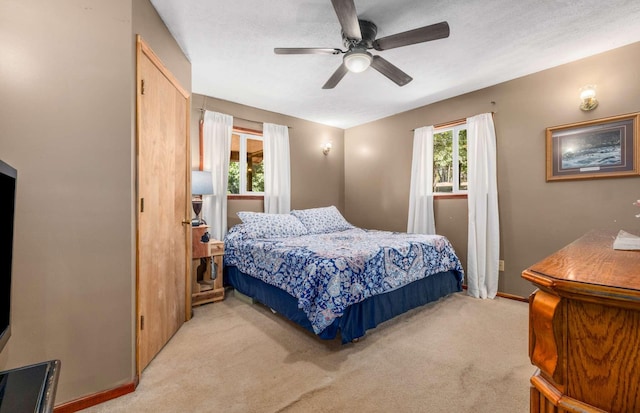 bedroom featuring light carpet, ceiling fan, a textured ceiling, and baseboards