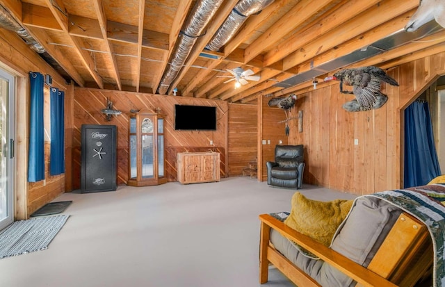 living room featuring concrete flooring, wood walls, and a ceiling fan