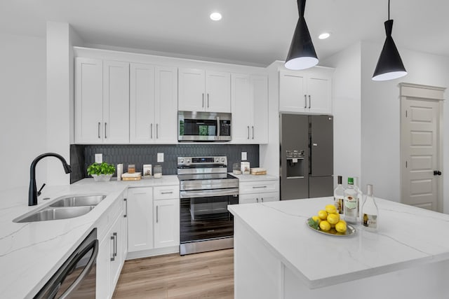 kitchen featuring light stone countertops, light hardwood / wood-style flooring, appliances with stainless steel finishes, sink, and white cabinets