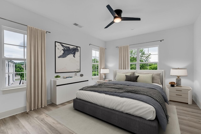 bedroom featuring light wood-type flooring, baseboards, visible vents, and a ceiling fan