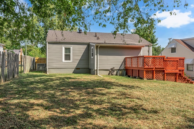 rear view of property featuring a wooden deck and a lawn