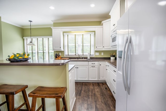 kitchen with dark hardwood / wood-style flooring, pendant lighting, crown molding, a breakfast bar, and white fridge with ice dispenser