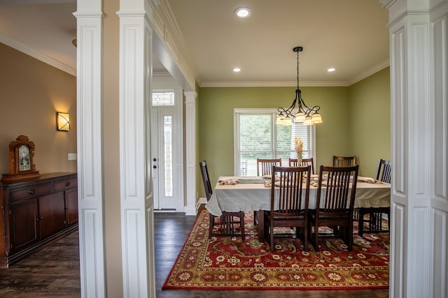 dining area with dark wood-type flooring, ornamental molding, decorative columns, and a notable chandelier