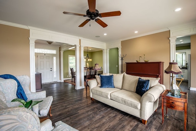 living room with ornamental molding, dark hardwood / wood-style floors, ceiling fan with notable chandelier, and ornate columns