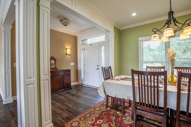 dining area with dark wood-type flooring, a chandelier, crown molding, and ornate columns