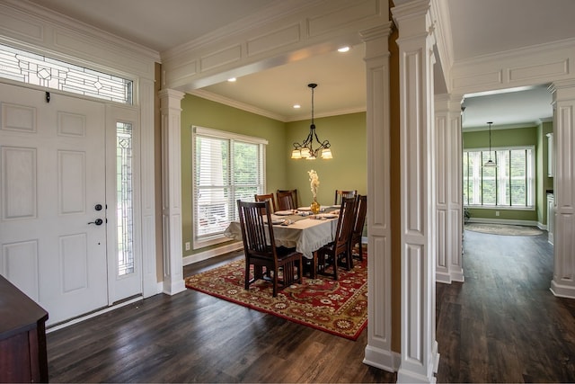 foyer featuring crown molding, dark wood-type flooring, an inviting chandelier, and ornate columns