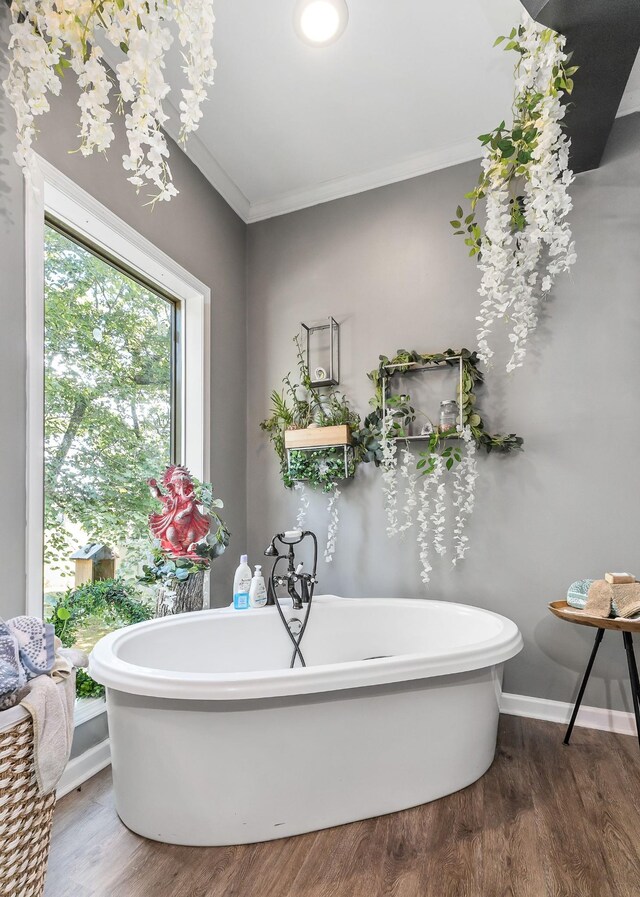 bathroom with a bath, hardwood / wood-style floors, and crown molding