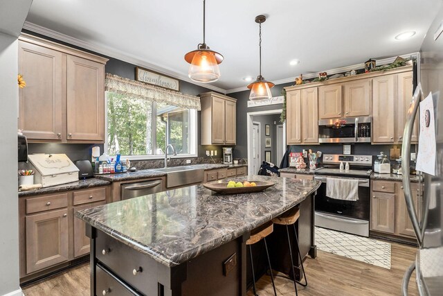 kitchen with dark stone countertops, a center island, light wood-type flooring, appliances with stainless steel finishes, and sink