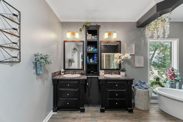 full bathroom with a freestanding tub, two vanities, ornamental molding, a sink, and wood finished floors