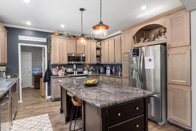 kitchen featuring dark stone countertops, a center island, crown molding, appliances with stainless steel finishes, and light hardwood / wood-style floors