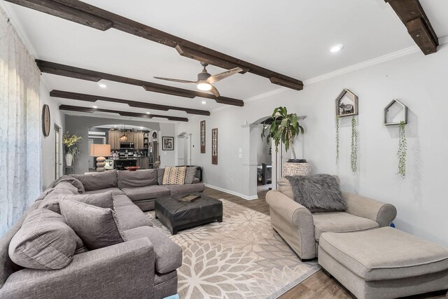 living room with crown molding, light hardwood / wood-style flooring, ceiling fan, and beamed ceiling