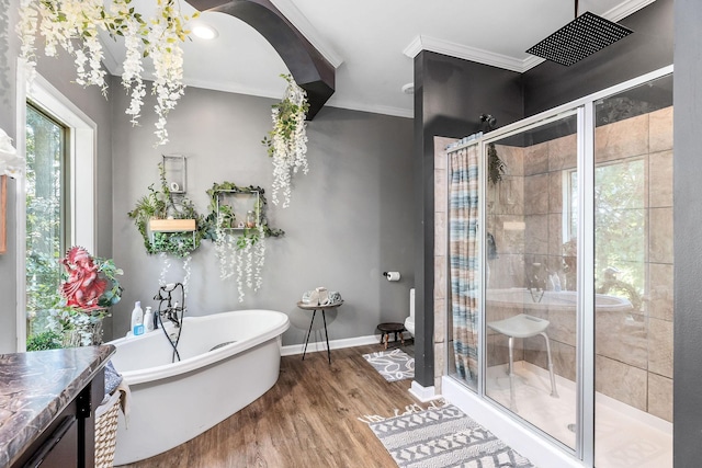 bathroom with wood finished floors, baseboards, a soaking tub, a stall shower, and ornamental molding