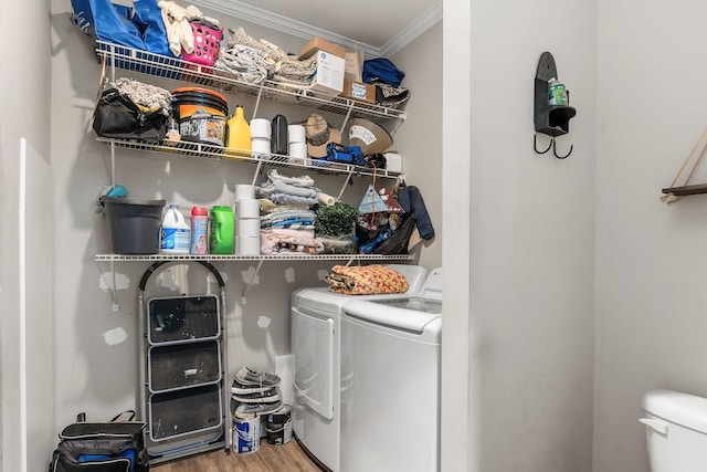 clothes washing area featuring laundry area, crown molding, wood finished floors, and washing machine and clothes dryer