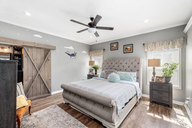 bedroom featuring a barn door, ceiling fan, ornamental molding, and hardwood / wood-style flooring