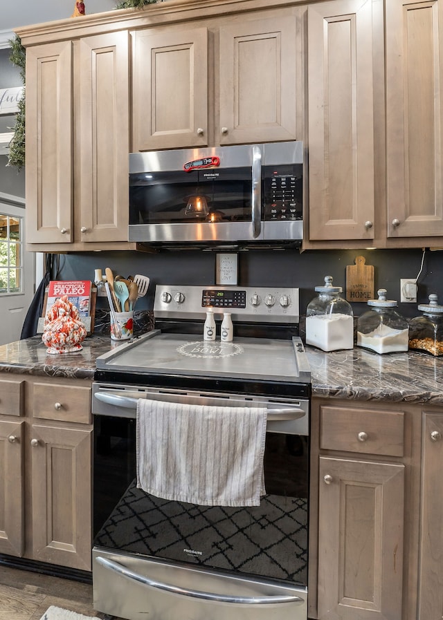 kitchen with appliances with stainless steel finishes and dark stone counters