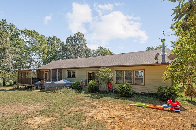 back of house with a yard, a sunroom, and roof with shingles