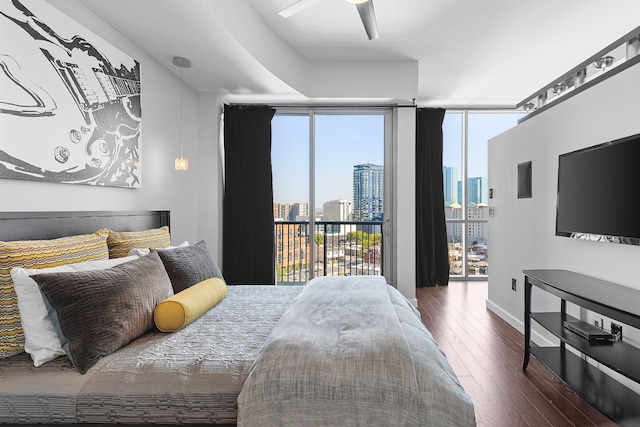 bedroom featuring dark wood-type flooring, a wall of windows, ceiling fan, and access to exterior