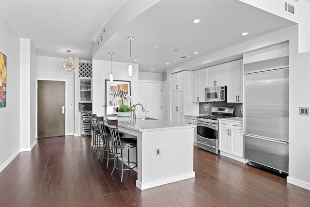 kitchen featuring sink, an island with sink, hanging light fixtures, appliances with stainless steel finishes, and white cabinets