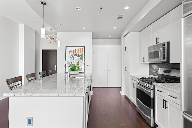 kitchen featuring a breakfast bar area, light stone countertops, a center island with sink, appliances with stainless steel finishes, and sink