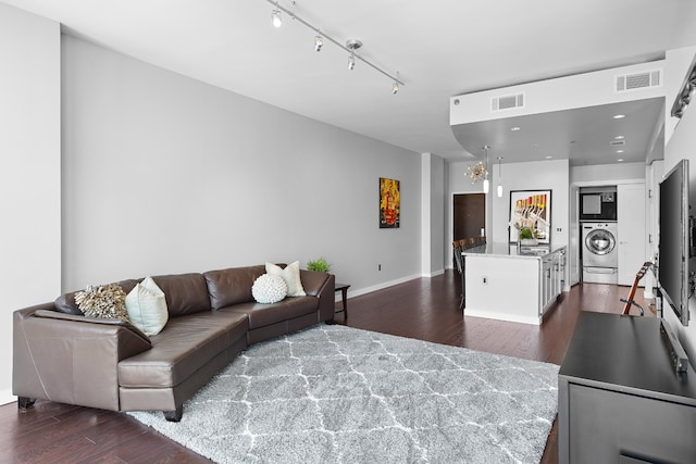 living room with washer / clothes dryer, rail lighting, and dark hardwood / wood-style floors