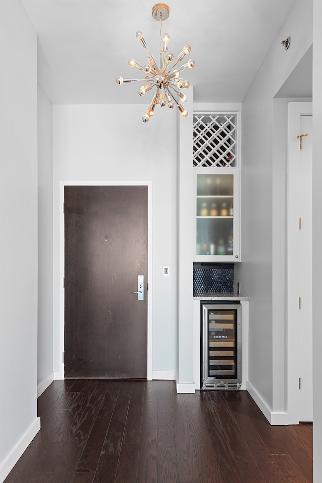 bar featuring dark hardwood / wood-style flooring, beverage cooler, decorative light fixtures, and a notable chandelier