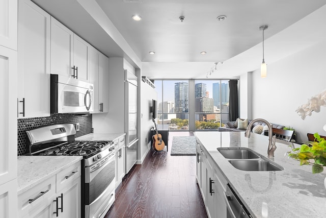 kitchen with light stone countertops, appliances with stainless steel finishes, dark wood-type flooring, sink, and white cabinets