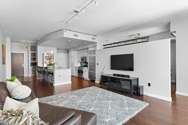 living room with dark hardwood / wood-style flooring, rail lighting, sink, and ceiling fan