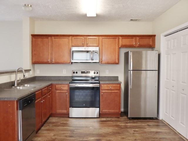 kitchen with a textured ceiling, stainless steel appliances, sink, and dark hardwood / wood-style floors