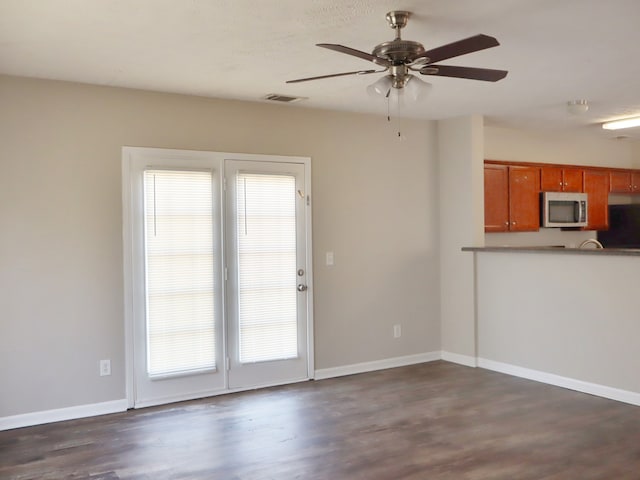 interior space with ceiling fan, a wealth of natural light, and dark hardwood / wood-style flooring