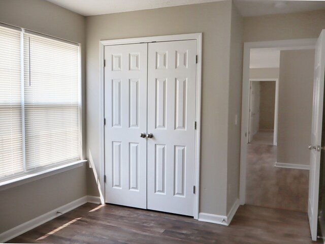 unfurnished bedroom with dark wood-type flooring and a closet