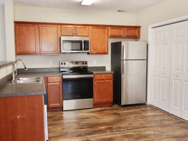 kitchen featuring a textured ceiling, stainless steel appliances, sink, and dark hardwood / wood-style flooring