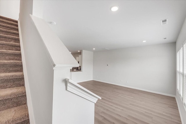 staircase with baseboards, wood finished floors, visible vents, and recessed lighting