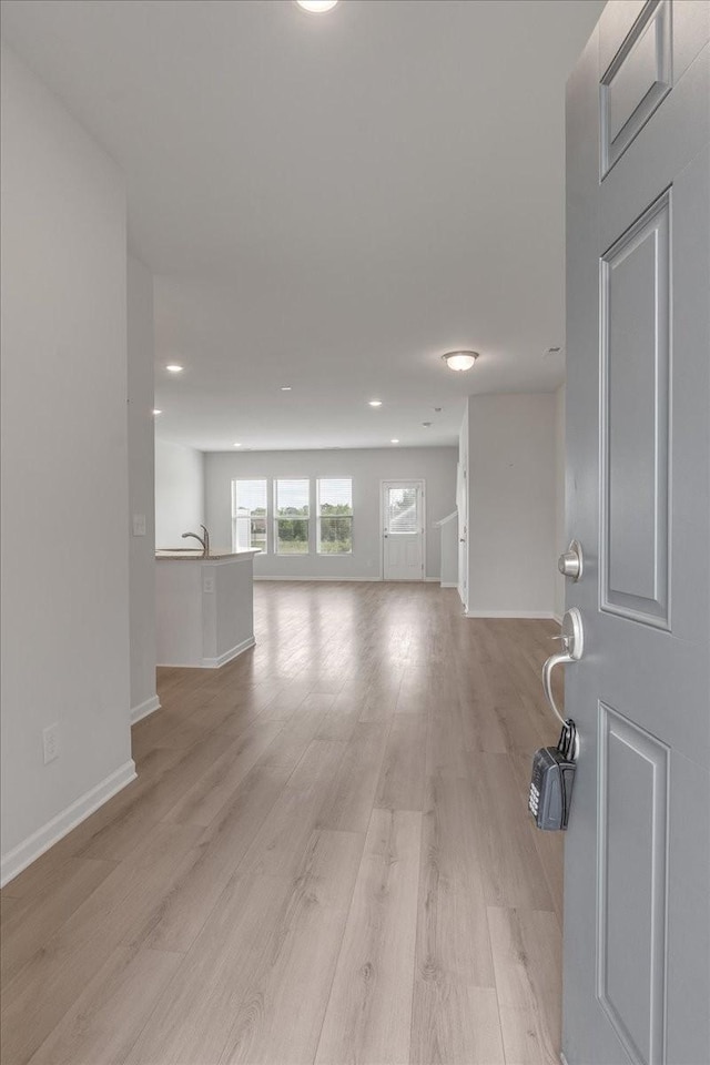 interior space with a sink, light wood-style flooring, and baseboards