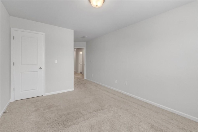 spare room with light carpet and baseboards