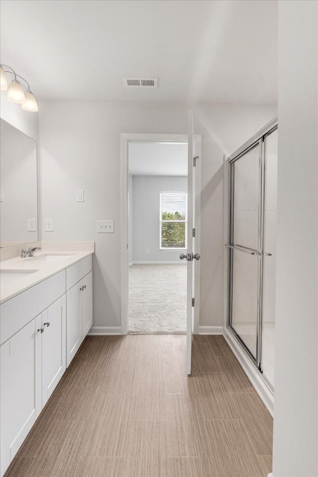 full bath featuring double vanity, a stall shower, visible vents, and a sink