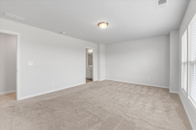 unfurnished room featuring baseboards, visible vents, and light colored carpet