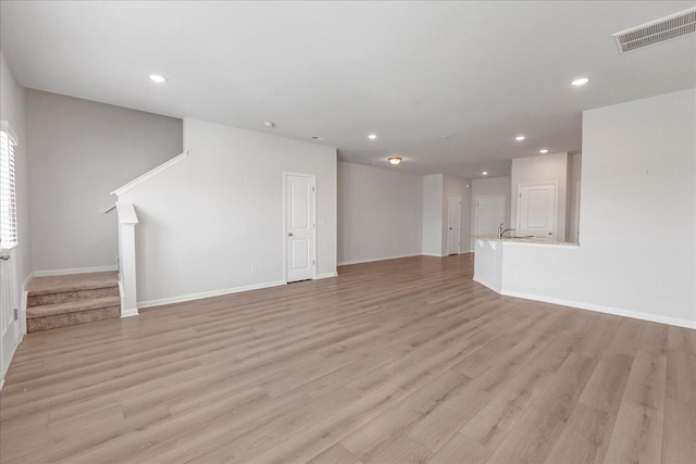 unfurnished living room with light wood-style flooring, stairs, visible vents, and recessed lighting