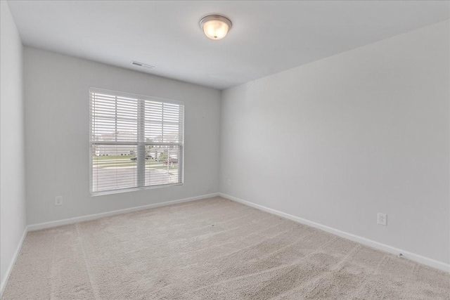 carpeted spare room with visible vents and baseboards