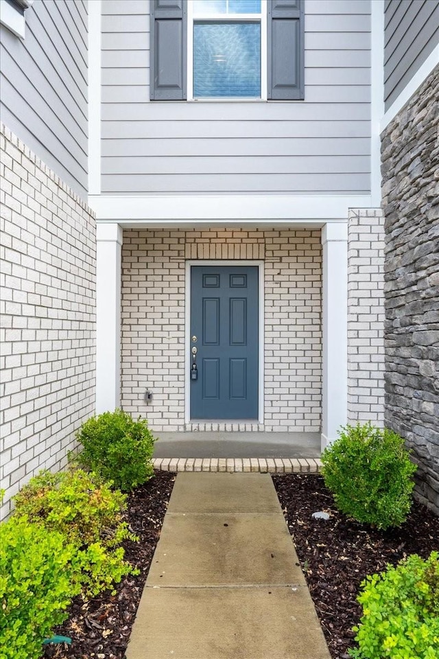 view of exterior entry featuring brick siding