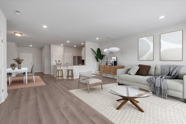 living room featuring recessed lighting, visible vents, and light wood finished floors