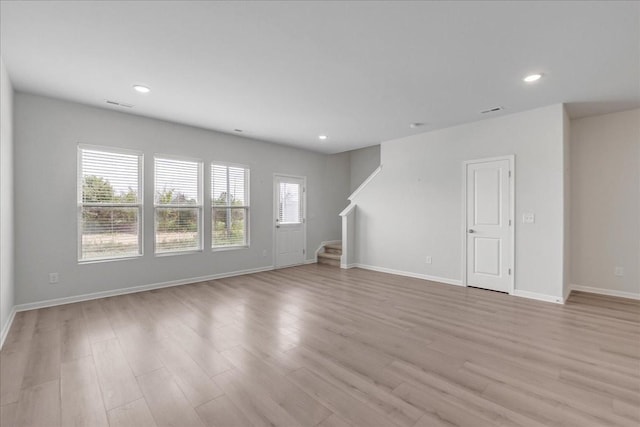 unfurnished living room with light wood-type flooring, stairway, baseboards, and recessed lighting