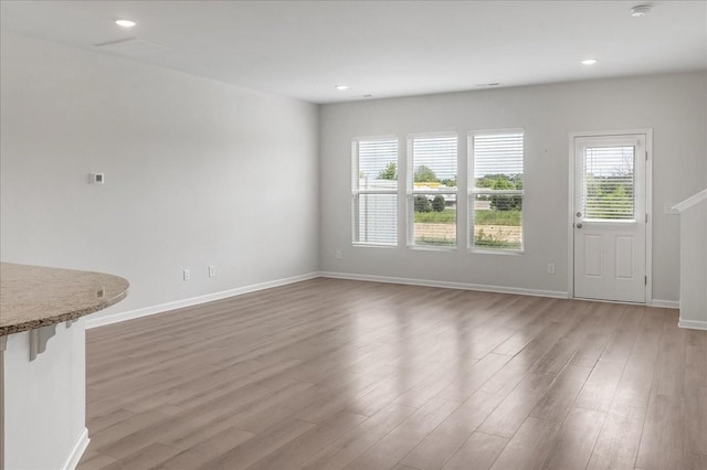 unfurnished living room with baseboards, recessed lighting, and light wood-style floors