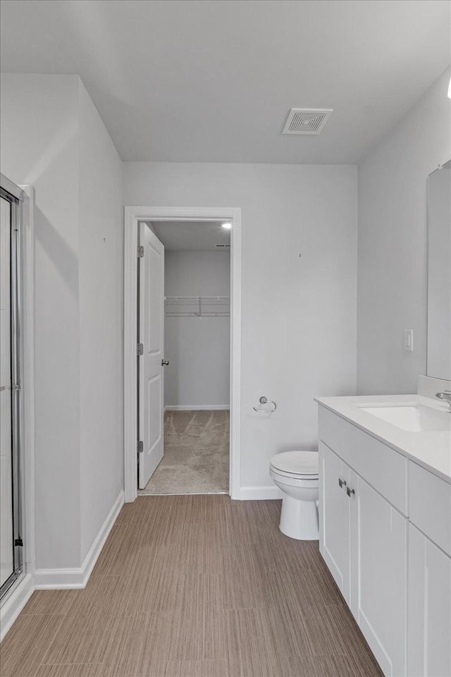 bathroom featuring toilet, wood finished floors, vanity, visible vents, and baseboards