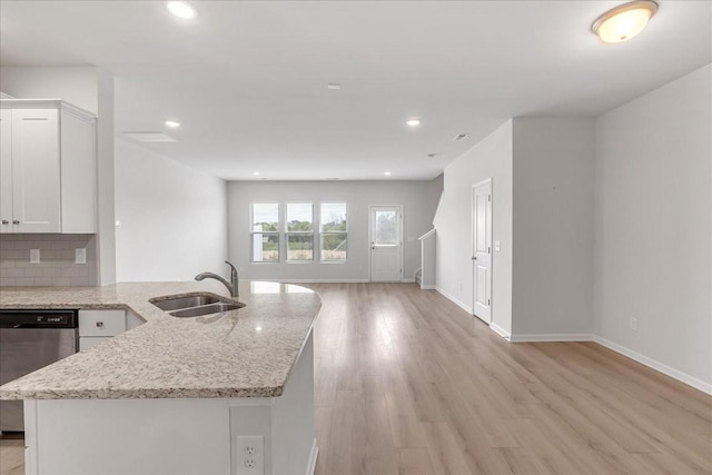 kitchen with light wood-style flooring, decorative backsplash, open floor plan, a sink, and dishwasher