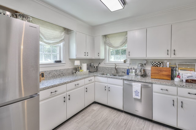 kitchen featuring white cabinets, stainless steel appliances, crown molding, and sink